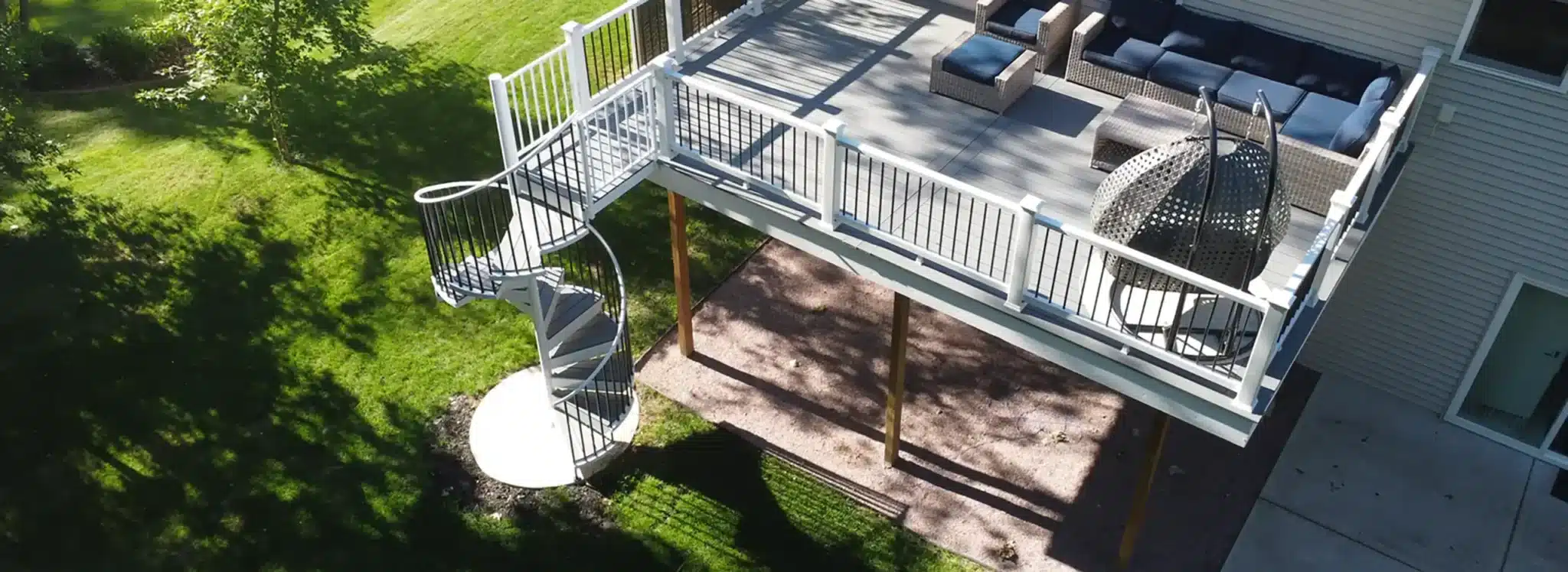 elevated deck with spiral staircase and patio beneath - Deck Building Company near me in Fitchburg, Wisconsin